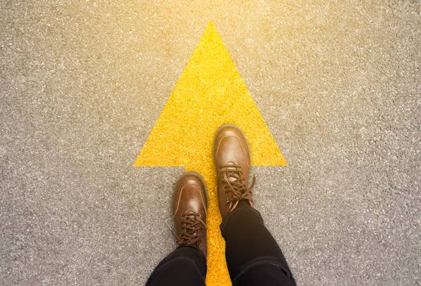 Person walking with a yellow arrow at their feet