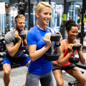Group of people training in a gym. They are smiling and holding weights.