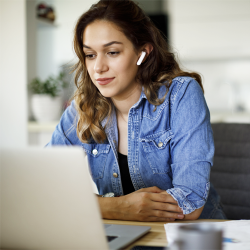 A person listening to a webinar on their laptop while wearing earpods
