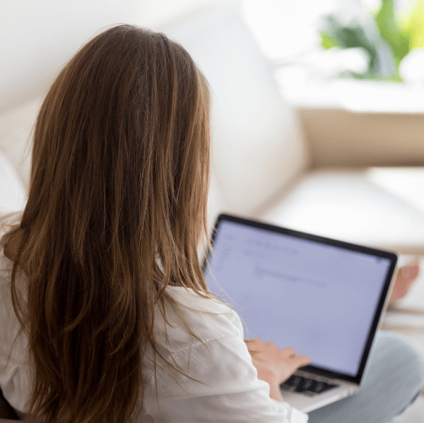 CPA updating resume and cover letter on laptop while sitting on sofa