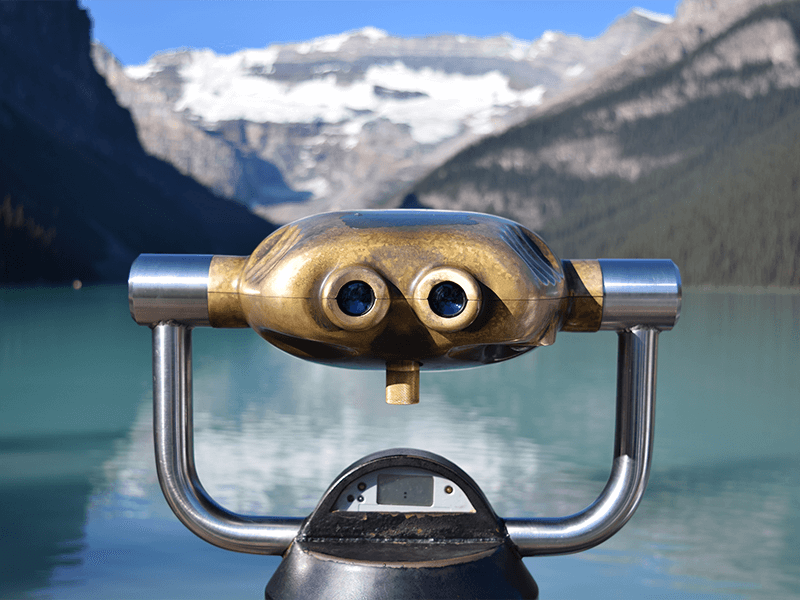 Binoculars in front of mountains and lake 