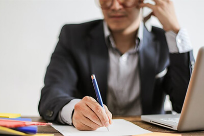 business person speaking on phone while taking notes